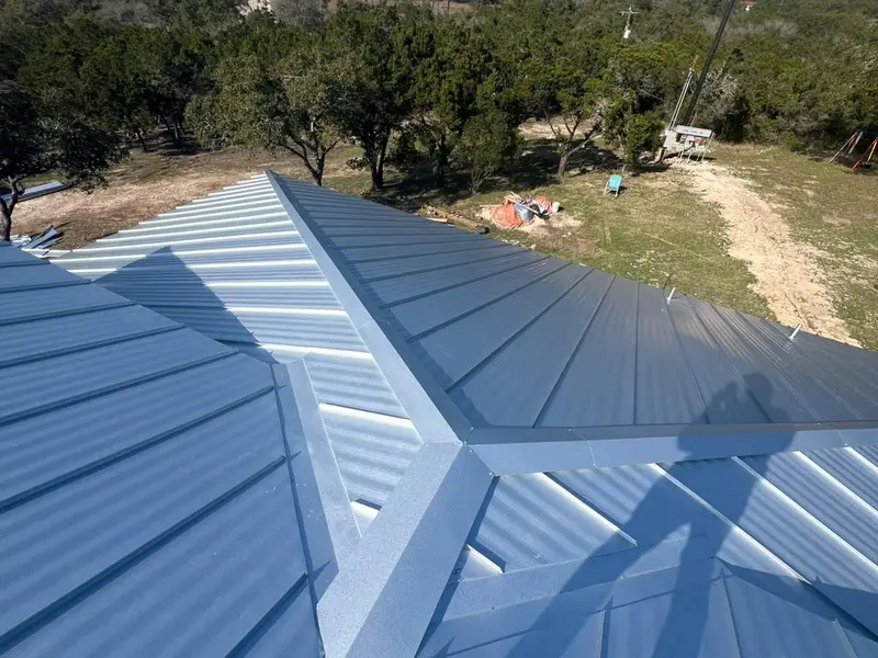 Silver standing seam metal roof on a hilltop home installed by RISE Roofing